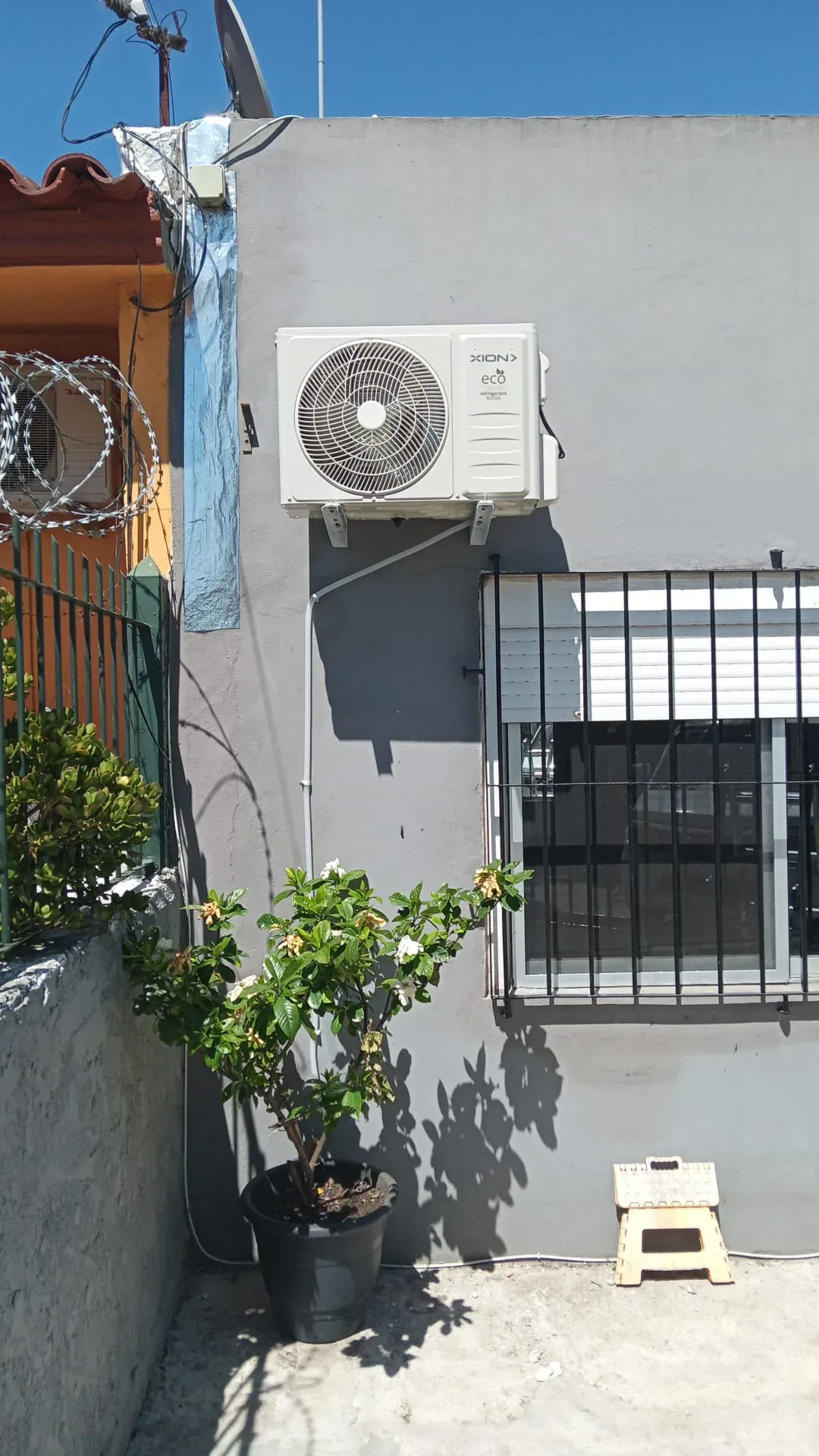 Unidad exterior de aire acondicionado Xion instalada en una pared exterior, con la cañería dentro de una canaleta